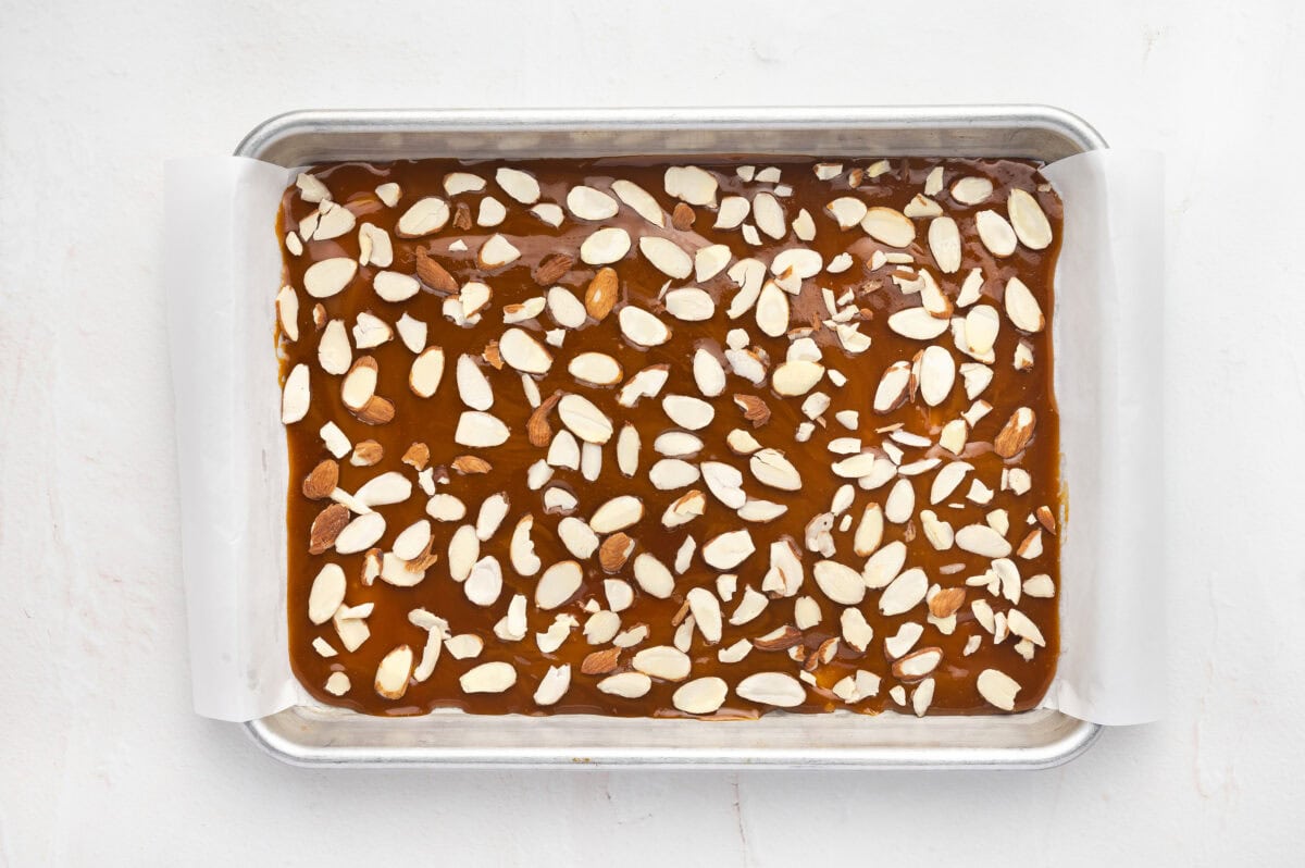 Sliced almonds on a baking sheet of toffee
