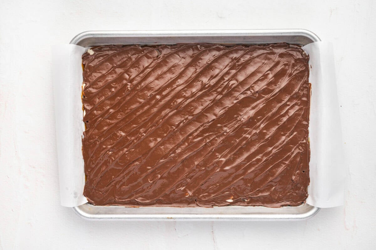 Melted chocolate spread on toffee in a baking sheet