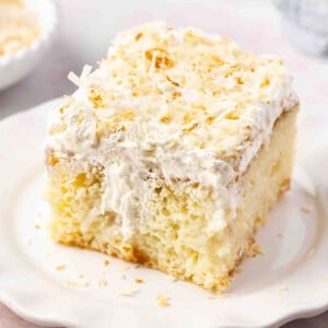 square slice of frosted coconut cake on plate