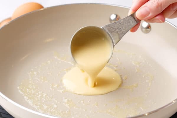 crepe batter being poured into fry pan