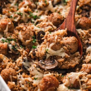 A wooden spoon in French onion meatballs and rice
