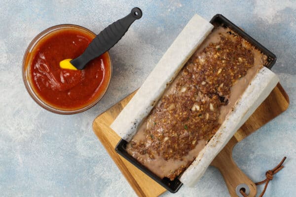 baked meatloaf in loaf pan and glaze in bowl