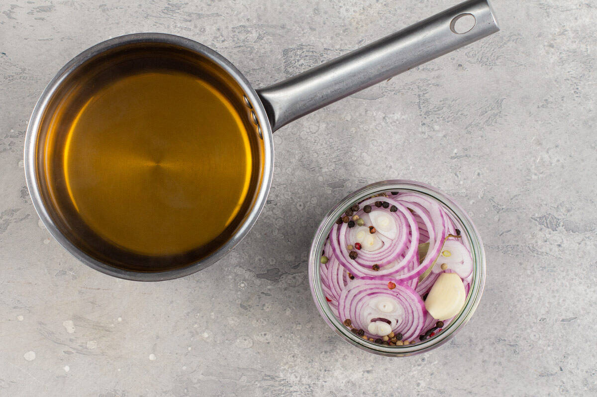 brine in pot and sliced red onions in jar