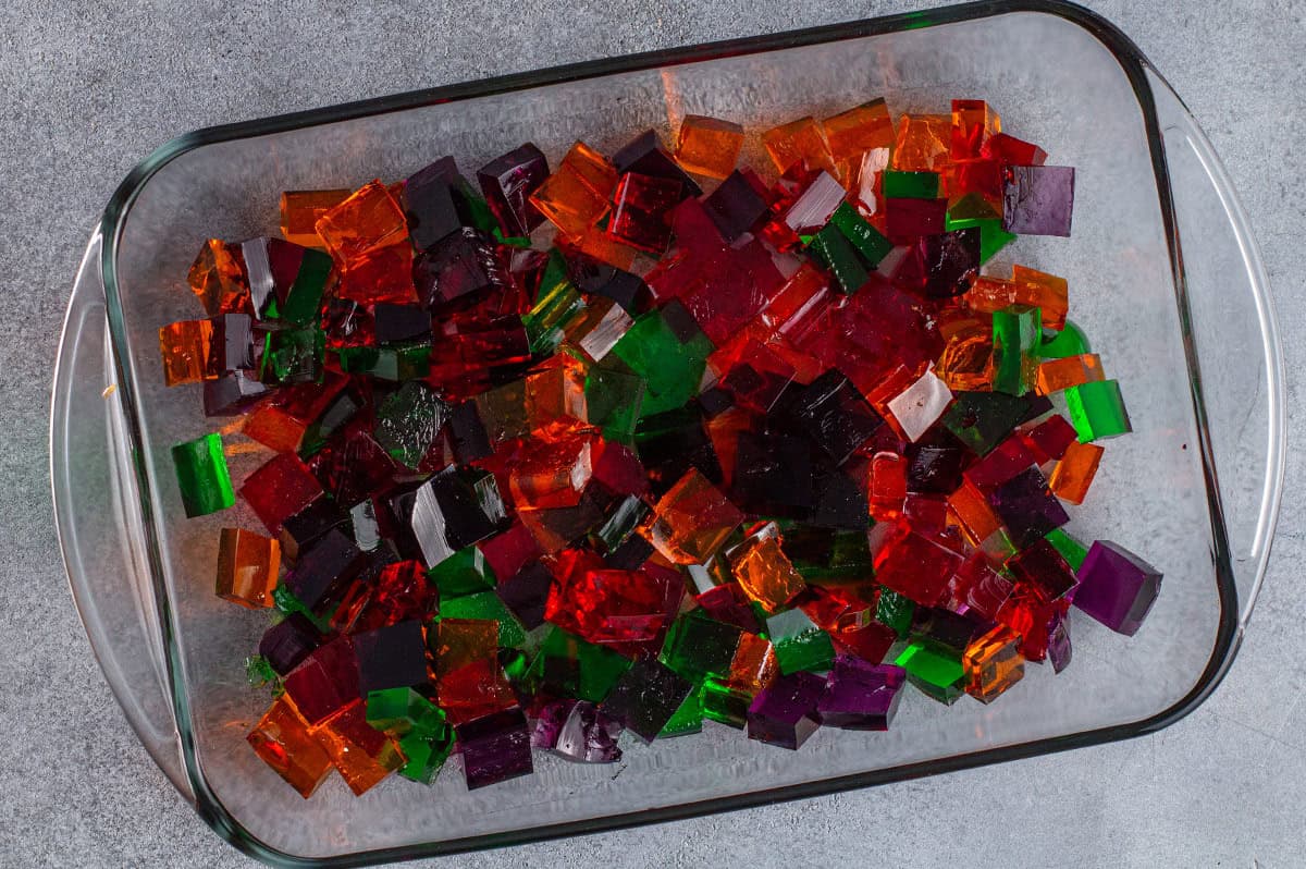 small cubes of orange, red, green, and purple jello in casserole dish