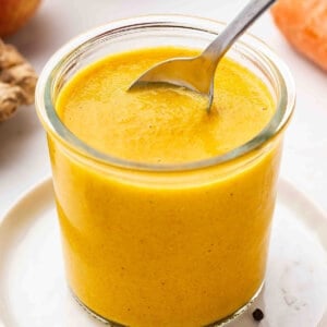 A spoon in a glass jar of Carrot-Ginger dressing