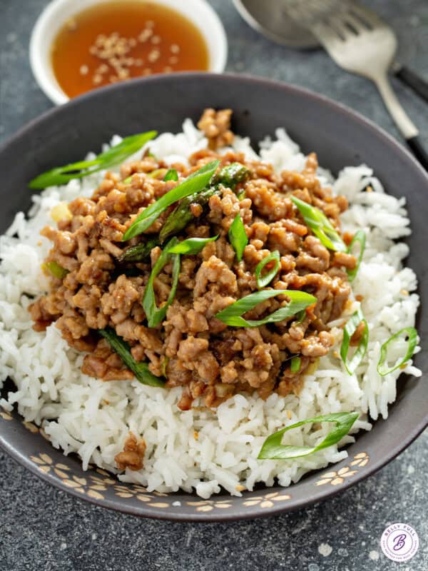 saucy ground pork stir fry on top of white rice in bowl