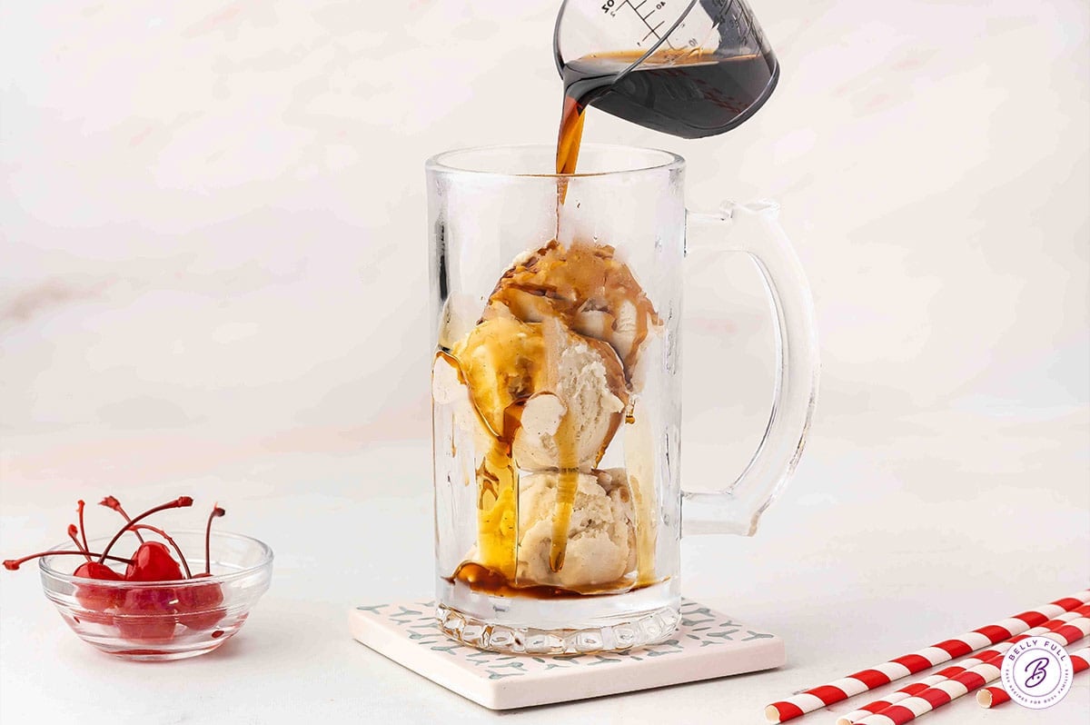 Pouring Kahlua over scoops of ice cream in a mug