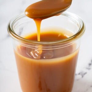 caramel sauce dripping off spoon into jar