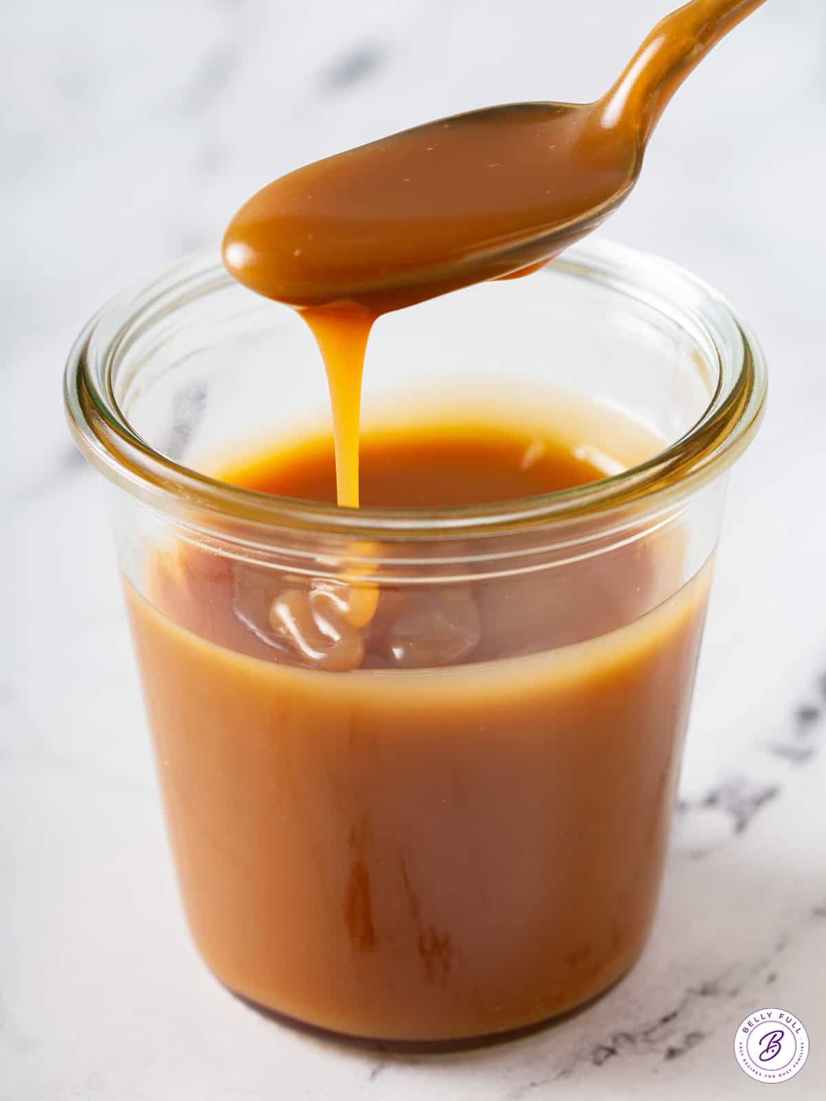 caramel sauce dripping off spoon into jar