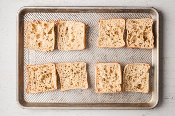 Sliced ciabatta rolls on a baking sheet