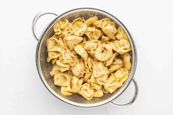 marinated tortellini draining in colander