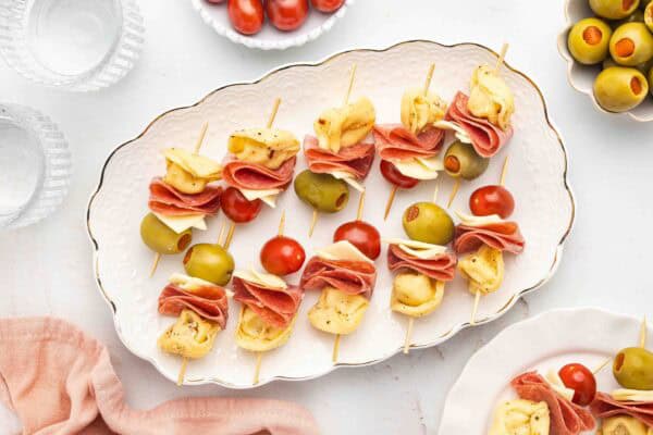 Mini Tortellini Kabobs with salami, cherry tomatoes, olives, and cheese on serving platter