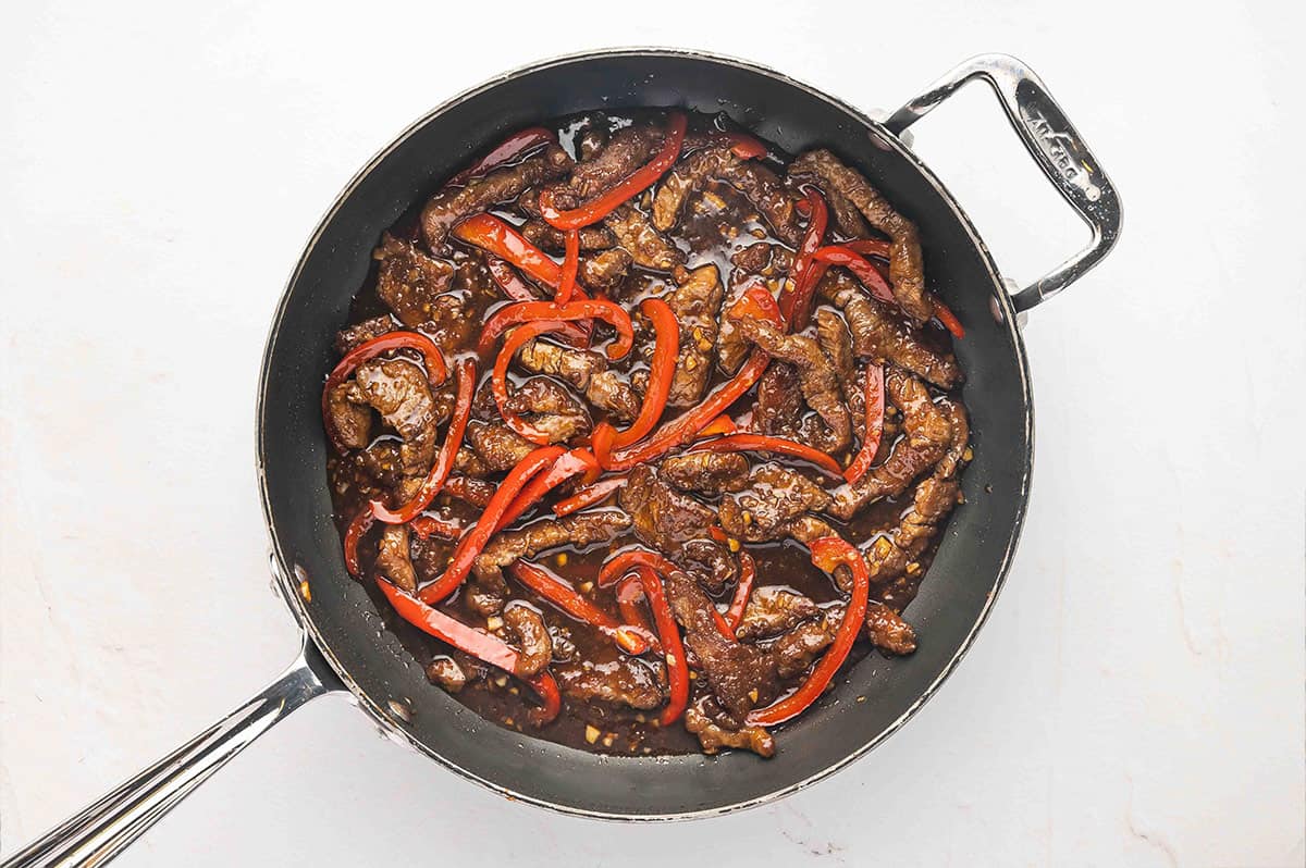 Flank steak and red peppers in a skillet