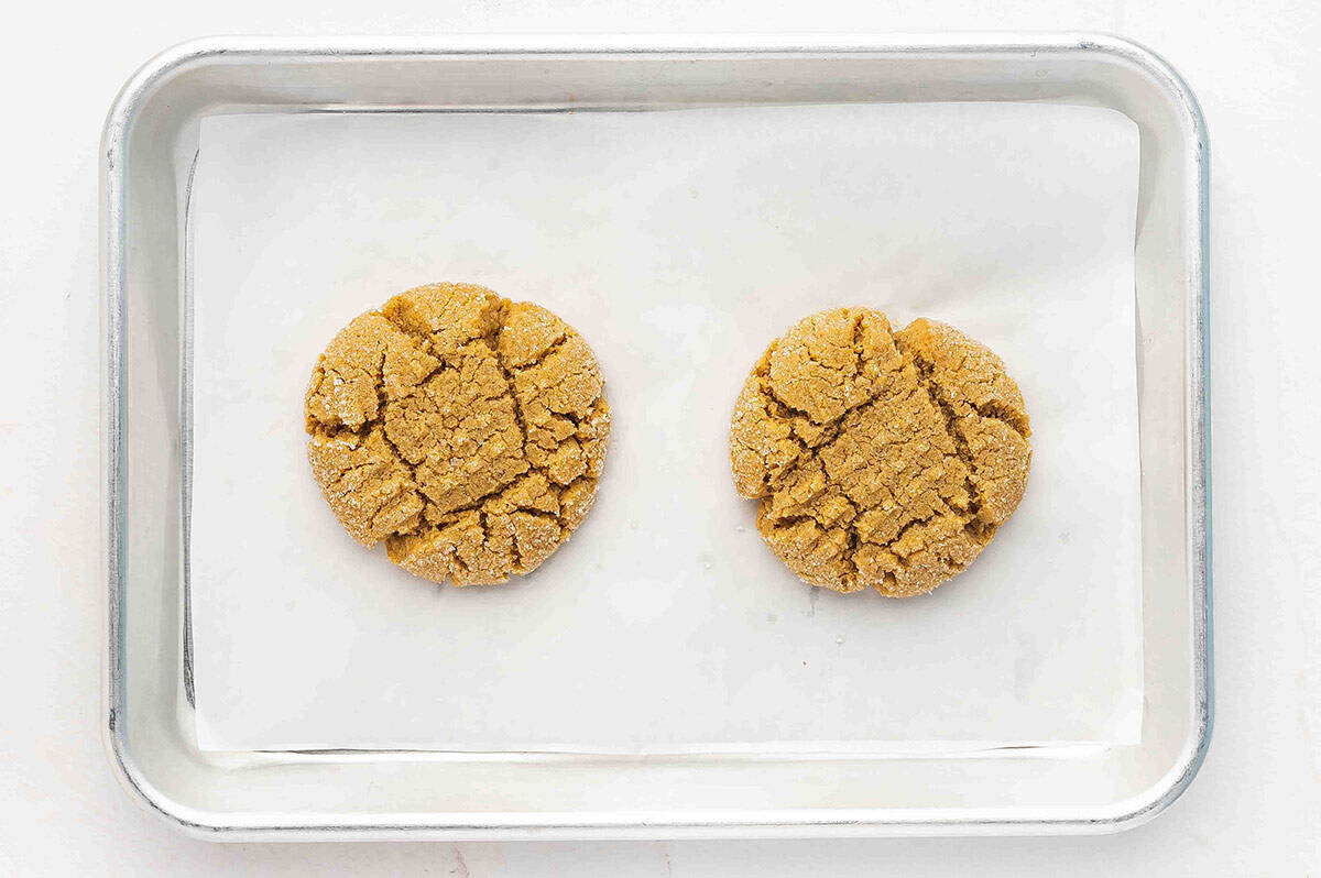 Overhead view of two peanut butter cookies on a baking sheet