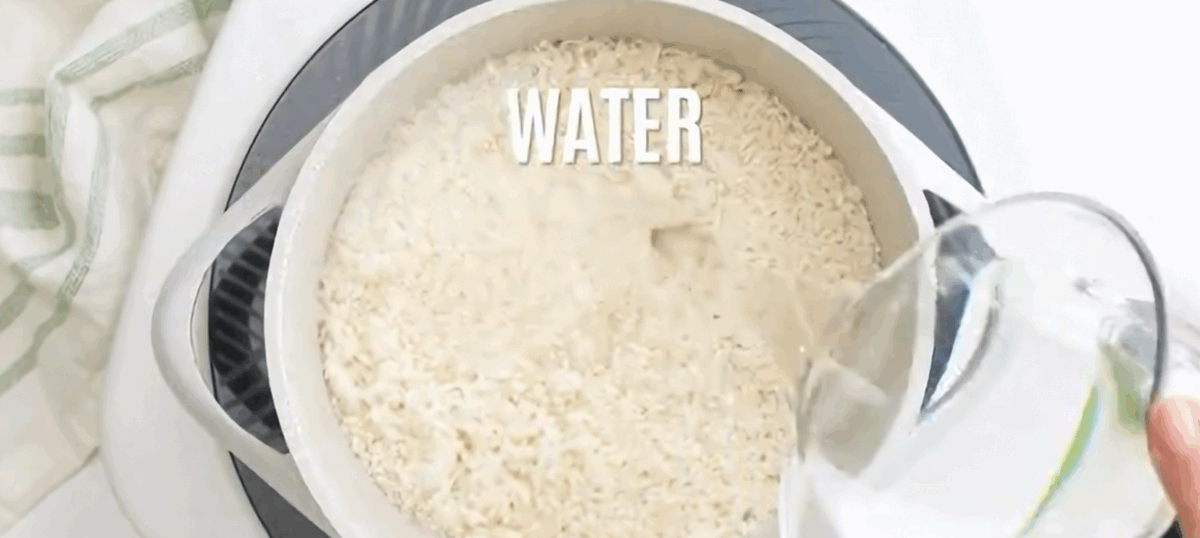 Adding water to the rice in a rice cooker.