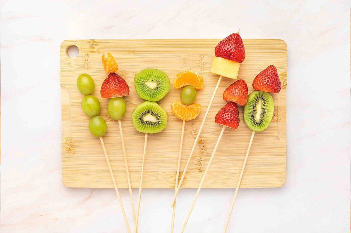 Fruit skewers on a wooden cutting board
