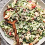 A wooden spoon in a bowl of apple date celery salad