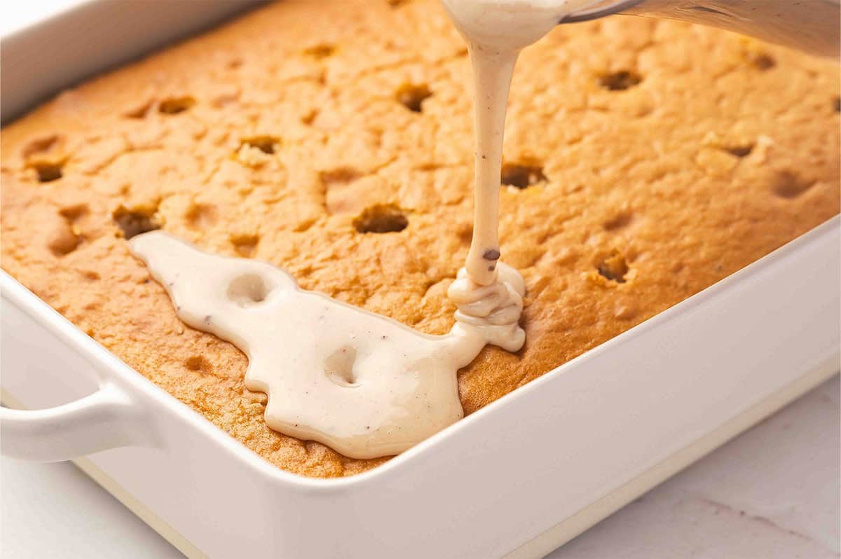 Pouring sweetened condensed milk over a poke cake