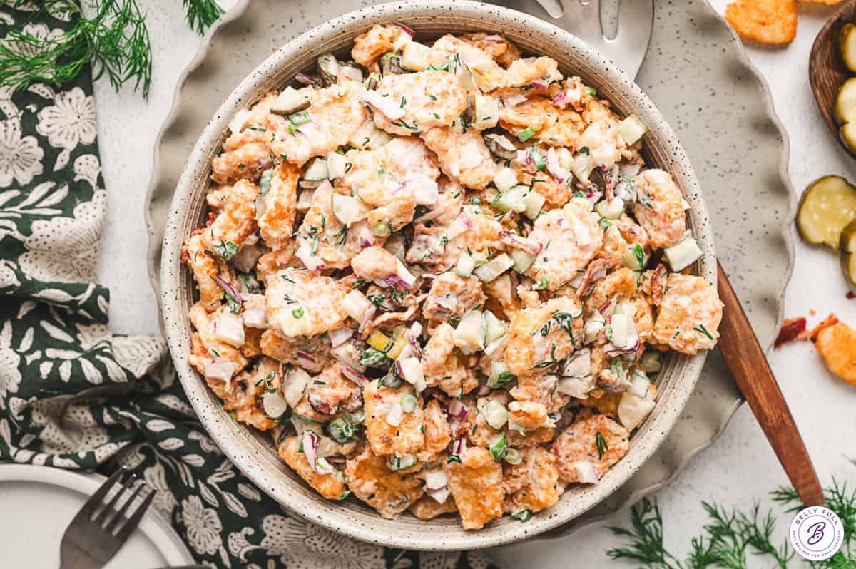 Crispy tater tots are tossed in a creamy dill dressing in this Dill Pickle Tater Tot Salad. A fun twist on classic potato salad. Overhead view of a bowl of tater tot salad