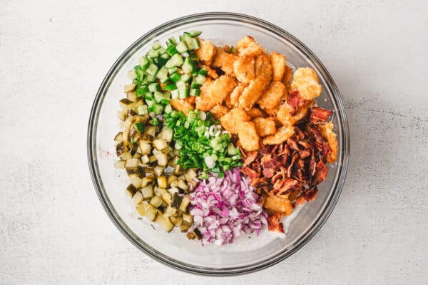 Tater tots, onions, bacon, and dill pickles in a bowl
