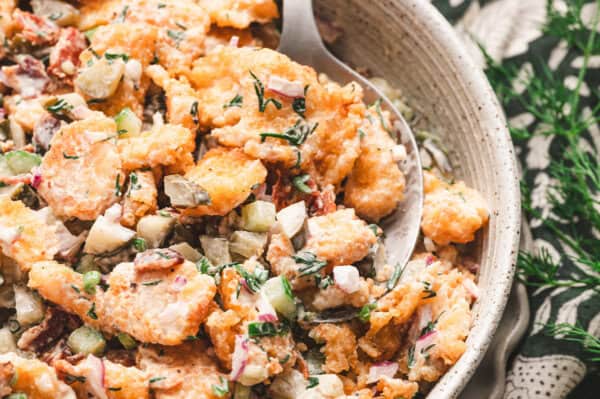 A spoon in a bowl of tater tot salad