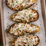 Baked stuffed eggplant halves filled with a golden breadcrumb and vegetable mixture, garnished with fresh parsley on a white plate.