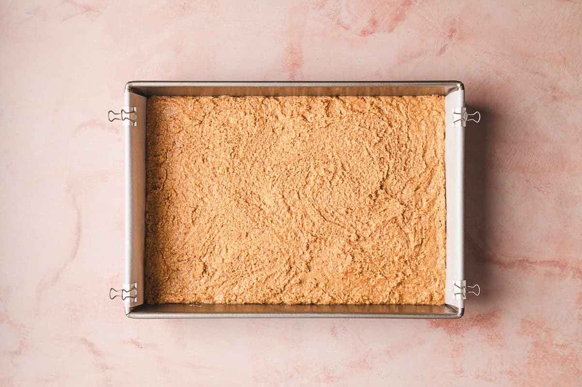 Thick peanut butter mixture fully combined and spread evenly in a square baking dish lined with parchment paper.