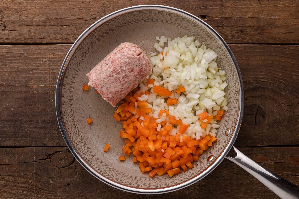 A spoon scooping out the flesh from a roasted eggplant half into a bowl.