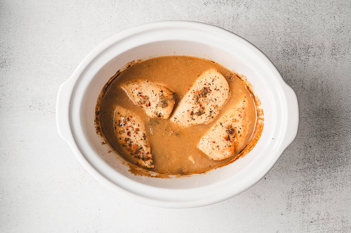 Chicken cooked and ready to be shredded, with visible gravy and seasoning.