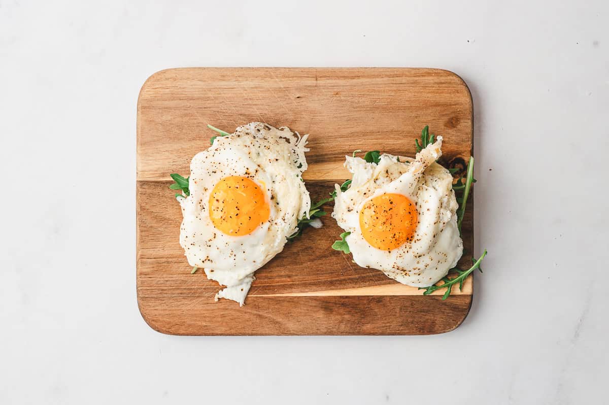 Frico eggs served on a plate with a side of avocado slices and toast.