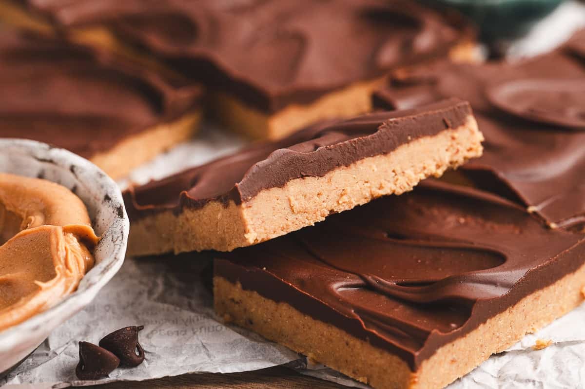 Close-up of sliced buckeye bars stacked on parchment, showcasing the layered peanut butter and chocolate textures.