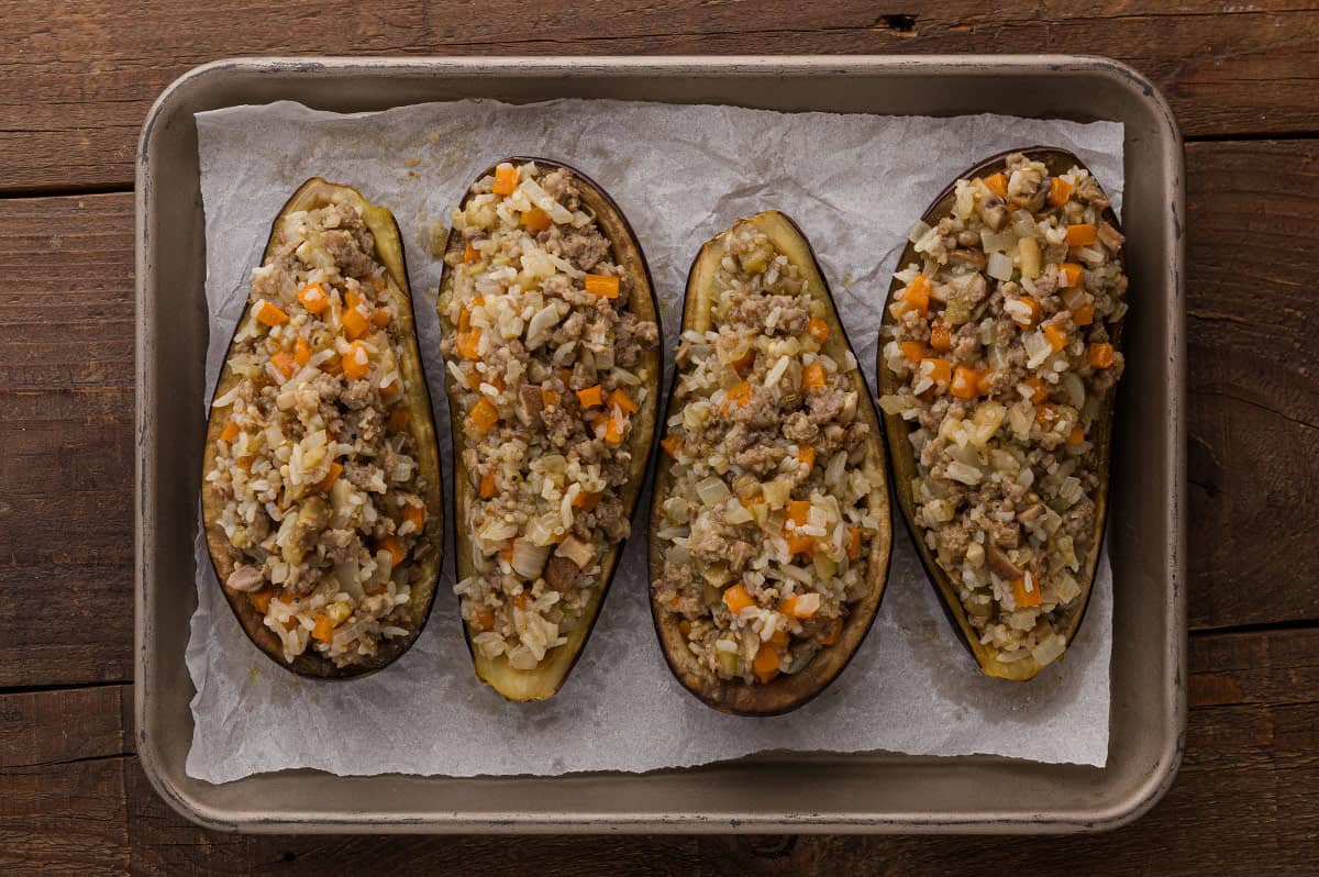 Cooked filling mixture spooned back into the hollowed eggplant shells.