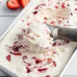 scoop of strawberry ice cream being rolled on solid ice cream