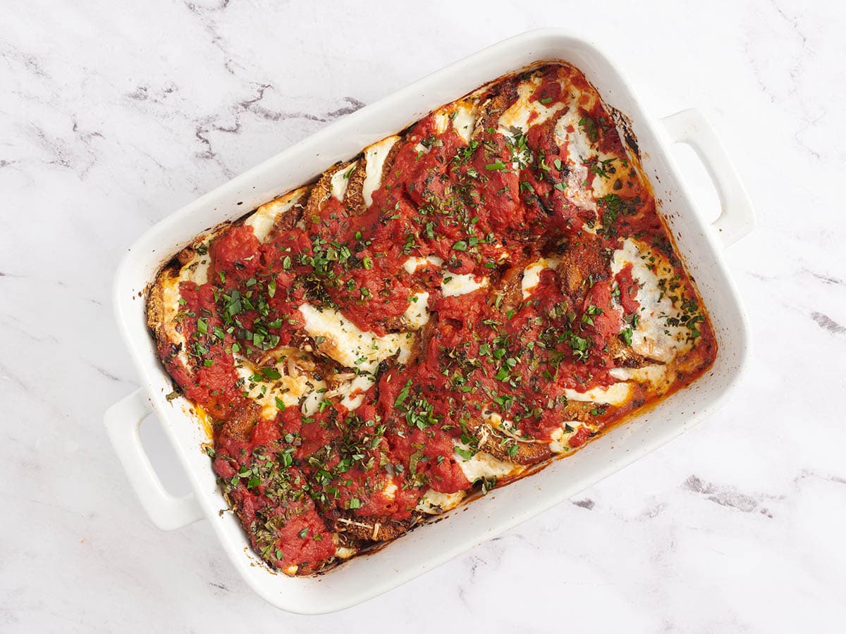 Baked eggplant parmesan in a white baking dish.