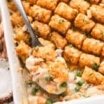 Overhead view of golden brown chicken tot pie baked in a white casserole dish, topped with rows of crispy tater tots.