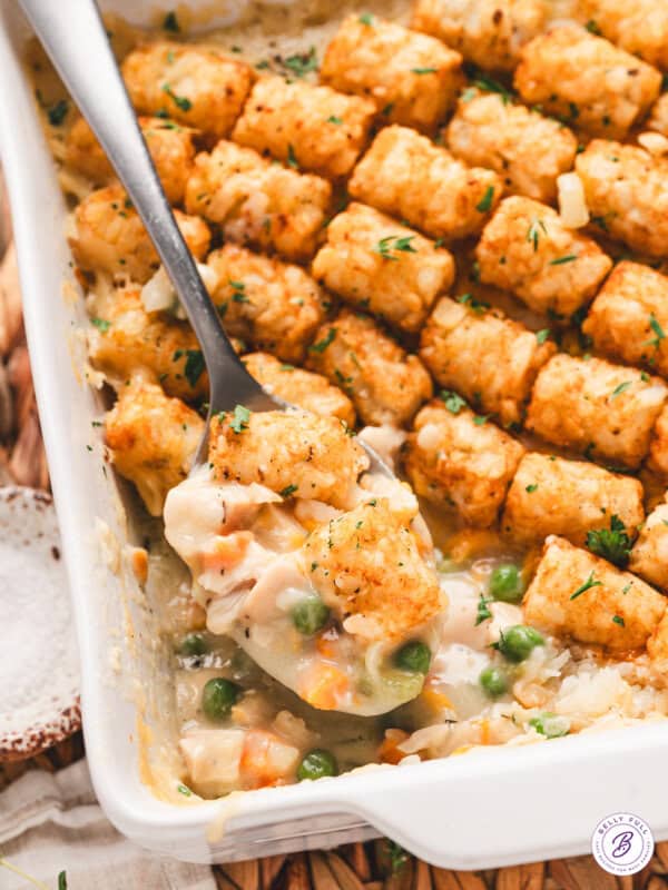 Overhead view of golden brown chicken tot pie baked in a white casserole dish, topped with rows of crispy tater tots.