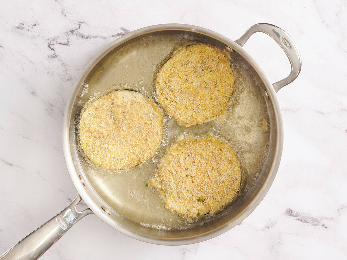 Breaded eggplant slices frying in a skillet for Eggplant Parmesan