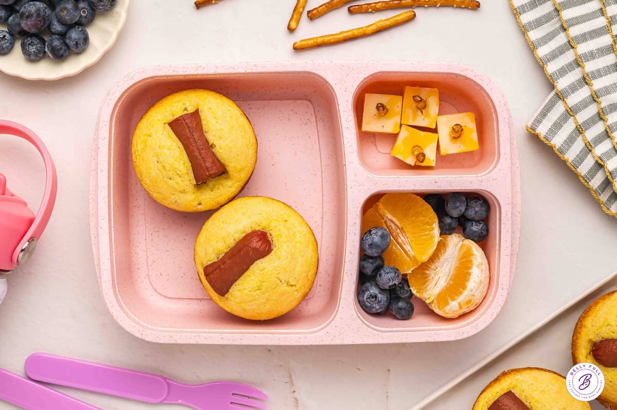 Corn dog muffins, cubed cheese, and fruit in bento box school lunch