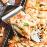 Crispy sheet pan crab rangoon pizza slice lifted from the pan, topped with melty cheese, crab, scallions, and sweet chili drizzle.