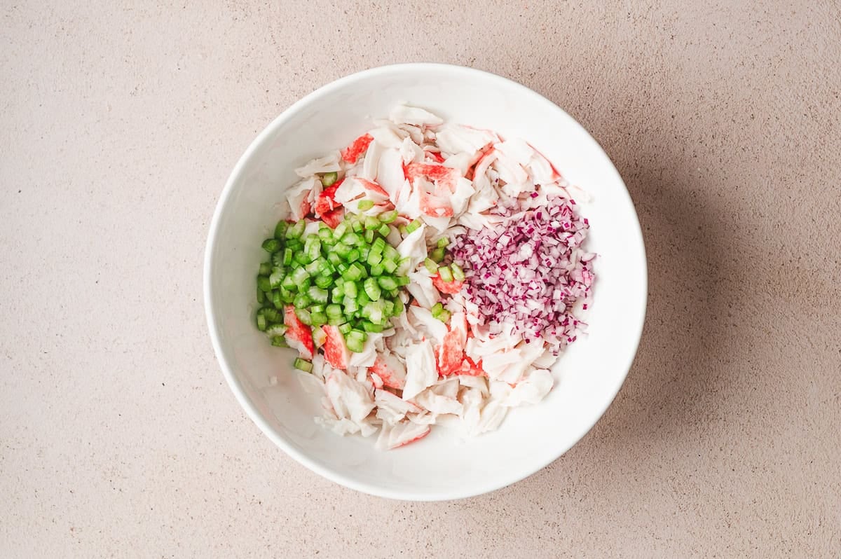imitation flaked crab meat, diced celery, and red onion in bowl