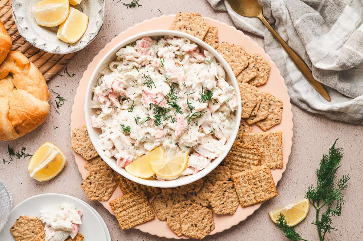 overhead dish of crab salad garnished with fresh chopped dill surrounded by crackers