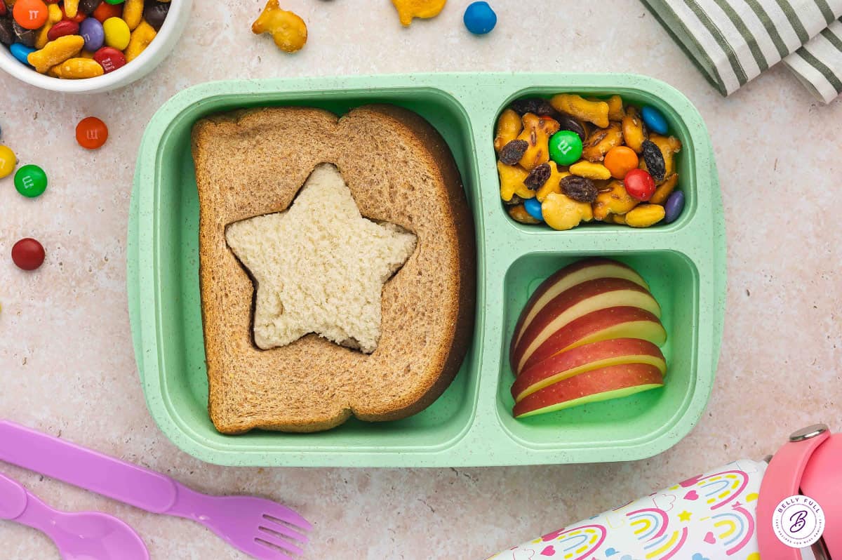Inside out white-wheat star sandwich, sliced apples, and trail mix in bento box for lunch