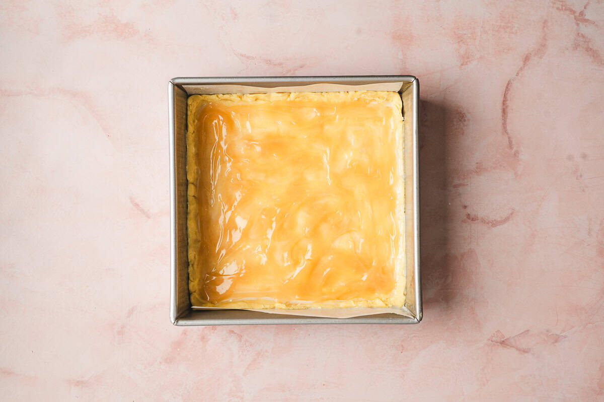 lemon curd spread on top of dough in a square baking dish