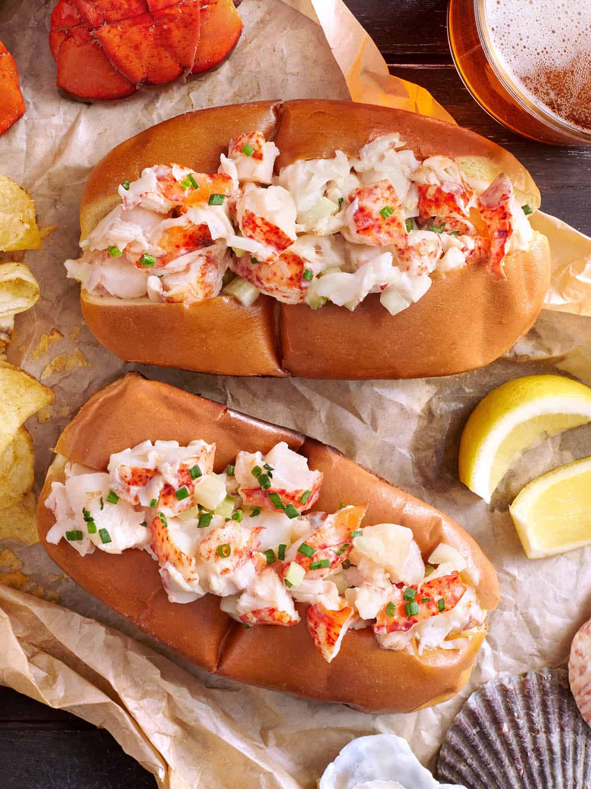 Close-up of two buttery toasted buns filled with lobster salad and garnished with fresh herbs.