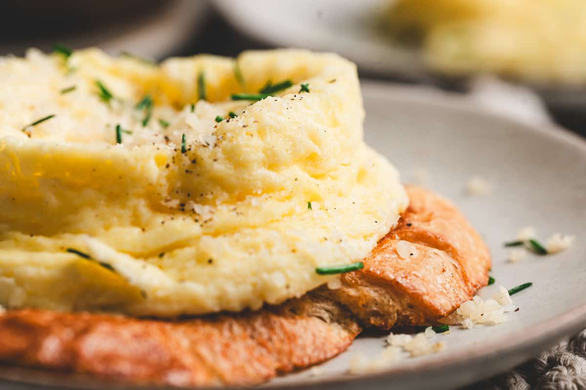 Fluffy soufflé-style egg sprinkled with Parmesan and fresh chives, sitting on a slice of golden toasted bread.