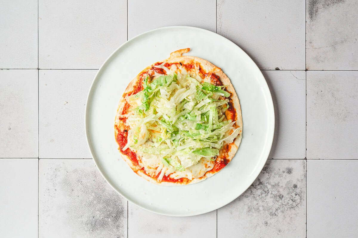 Air-fried cheesy tortilla topped with seasoned shredded lettuce before folding.