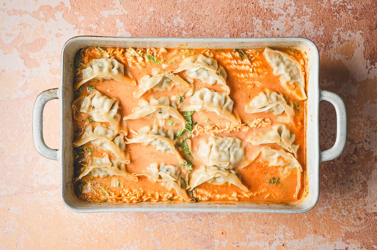 Casserole dish after baking, showing cooked dumplings sitting on top of the ramen in the thickened curry sauce.