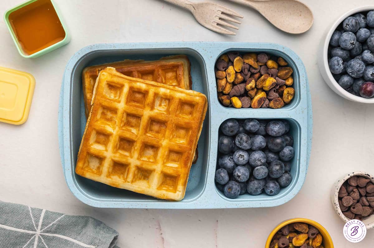bento box for lunch with waffles, blueberries, pistachios, and chocolate chips