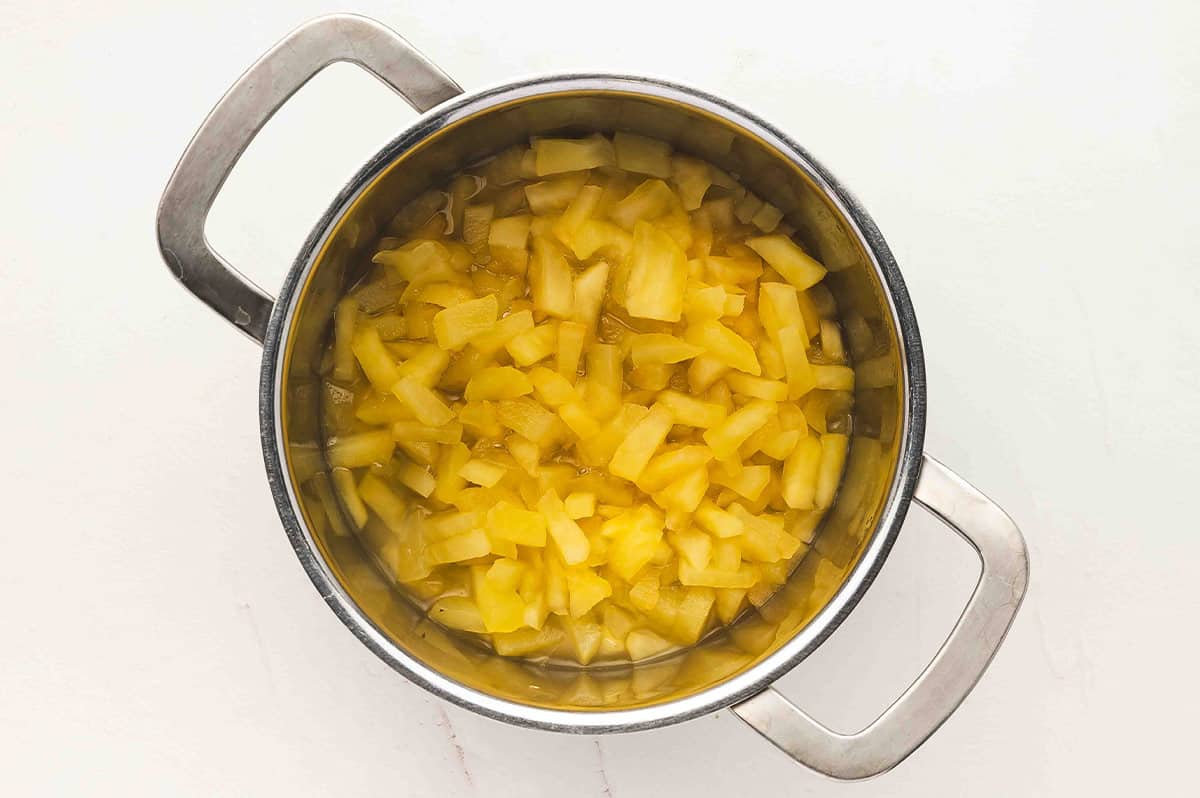 Pot of chopped apples simmering in water until softened.
