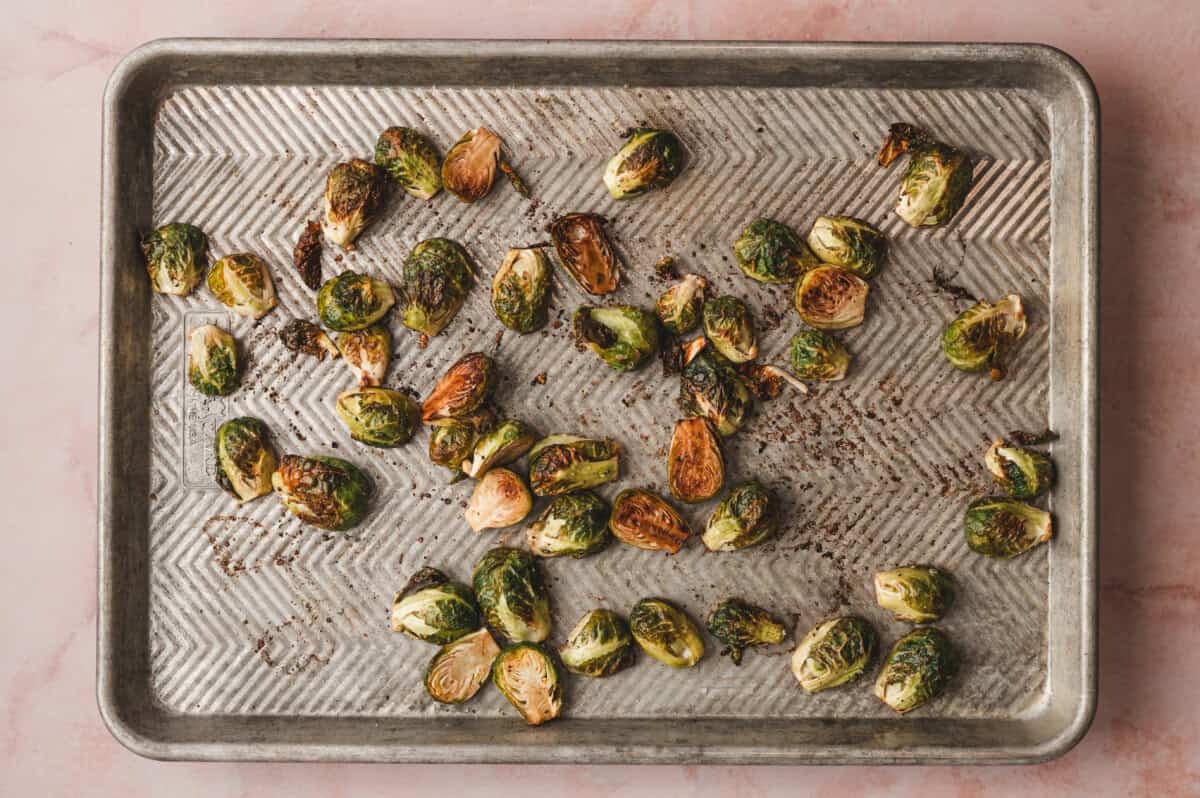 Roasted brussels sprouts on a baking sheet with dark golden edges, fully caramelized after roasting.